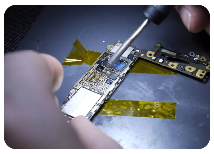 Technician micro soldering an iPhone logic board under a microscope for board level repair in Edmonton